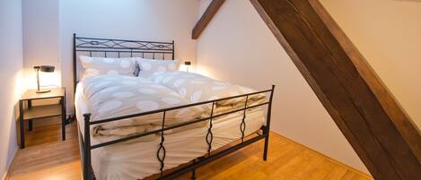 Ein Schlafzimmer mit Bett, Nachttischen und einer geneigten Decke.