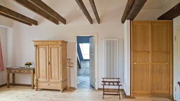 A room with wooden flooring, a large wooden cabinet, a small table with a vase, a radiator, and a wooden door.