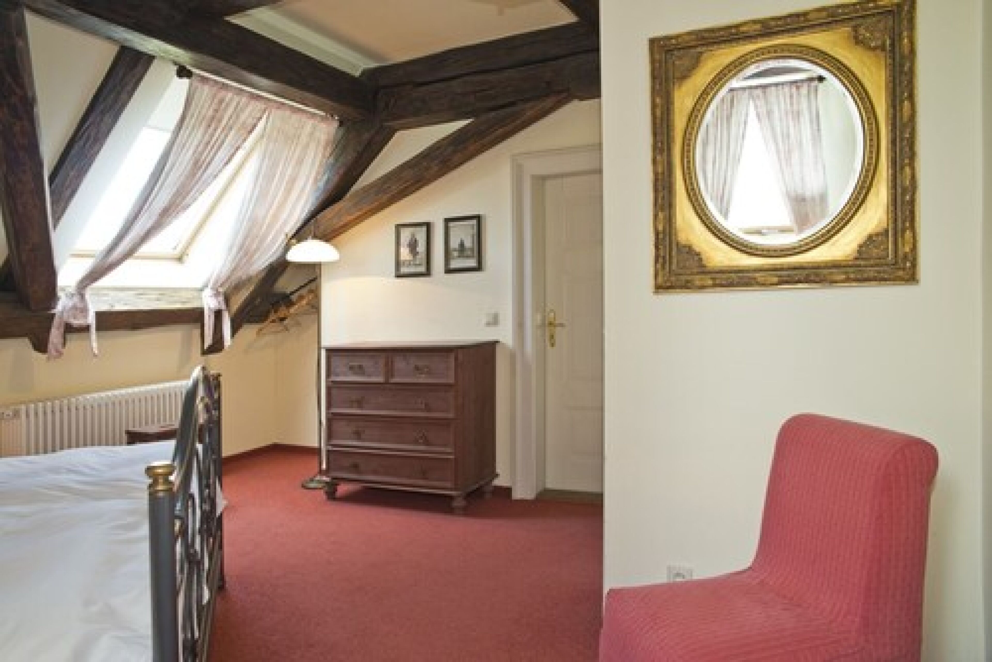 A bedroom with a bed, a dresser, a chair, and a mirror.