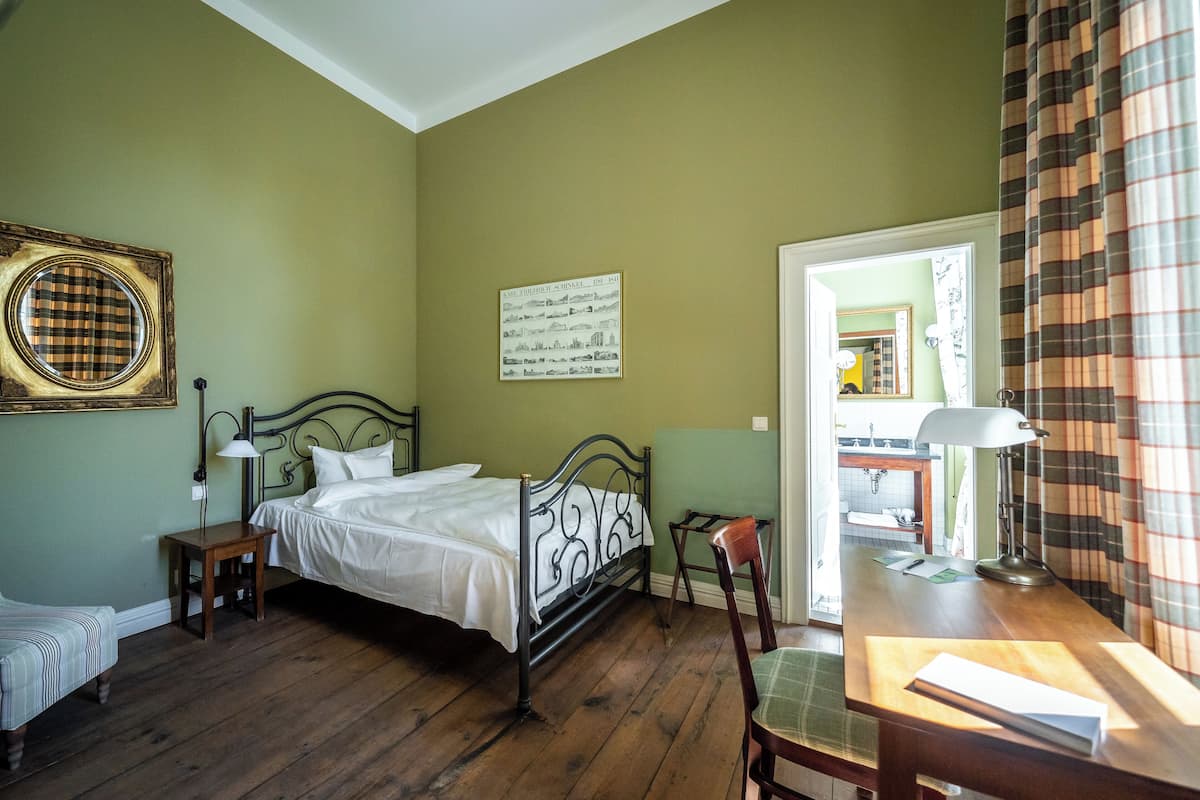 Una habitación con una cama, un escritorio, una silla, una lámpara y un cuadro en la pared.
