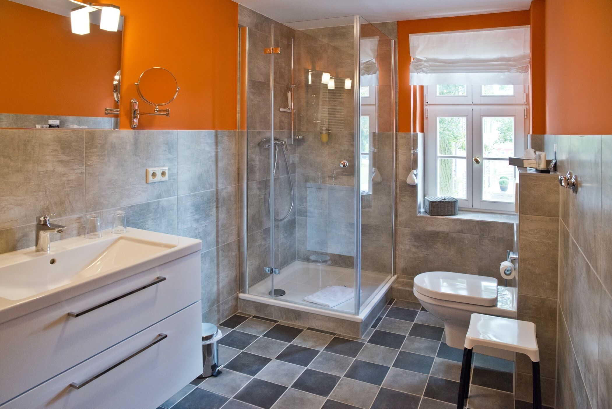 Ein modernes Badezimmer mit einer Duschkabine aus Glas, einem weißen Waschbecken und einer Toilette.