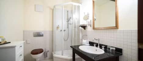Un baño con inodoro, cabina de ducha, lavabo y espejo.