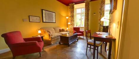 A living room with a red ceiling, yellow walls, a sofa, two armchairs, a coffee table, and a dining table with chairs.