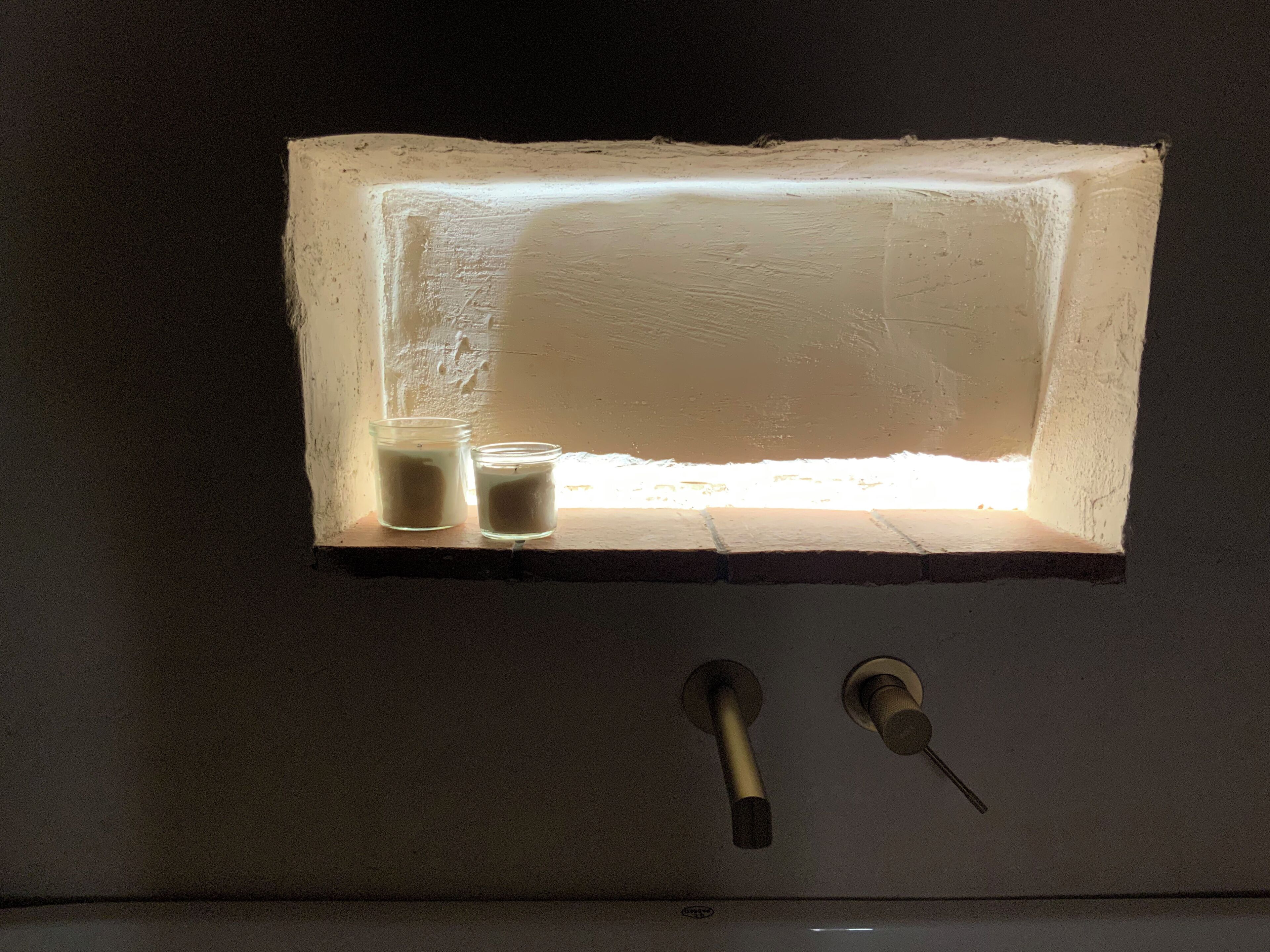 A rectangular light fixture with a frosted glass cover, two small glass containers, and a keyhole below.