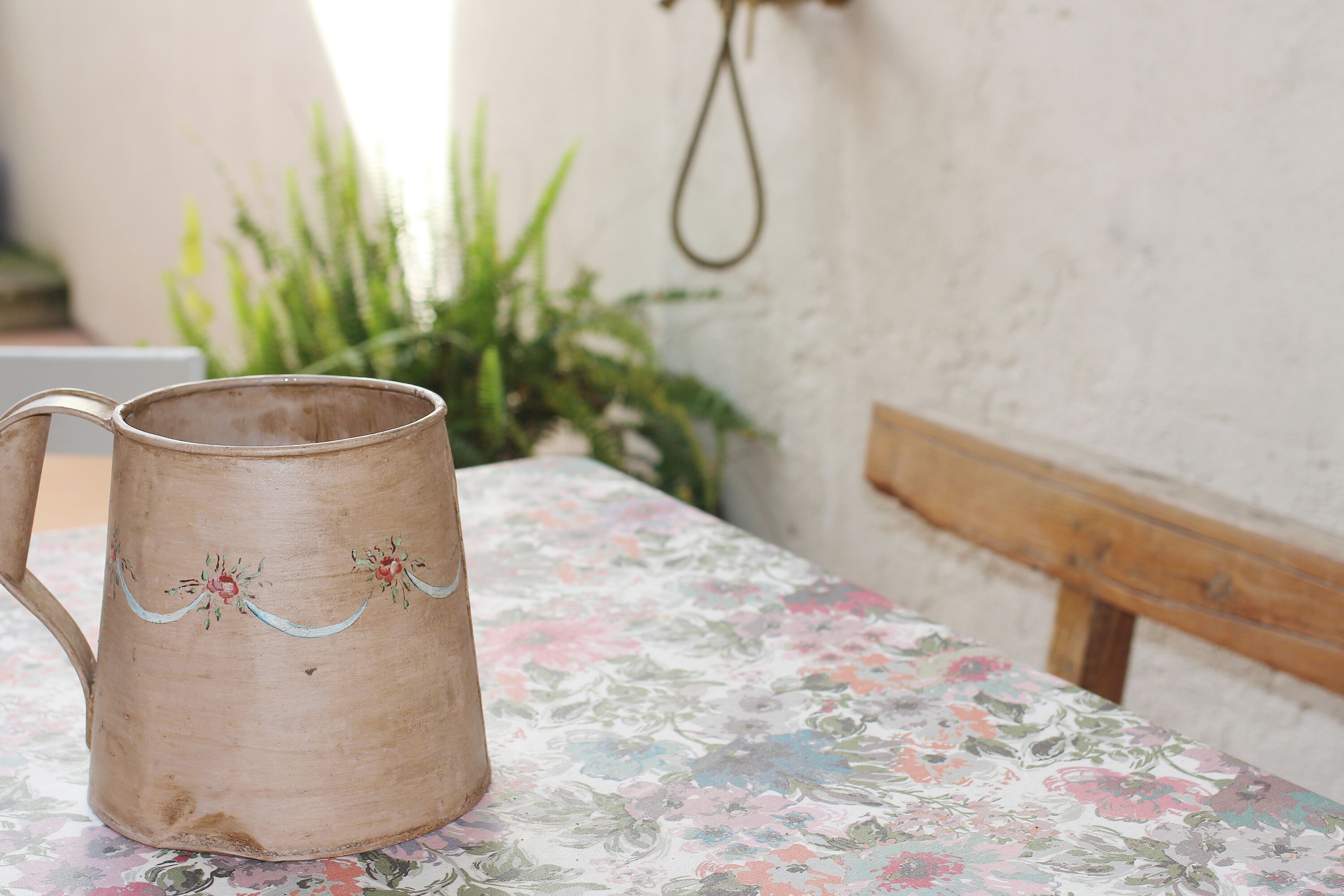 Una jarra de madera rústica con diseños florales sobre un mantel floral.