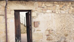 A stone building entrance with a wooden door, a potted plant, and a mailbox. - La Grulla Dorada (Perales del Puerto)