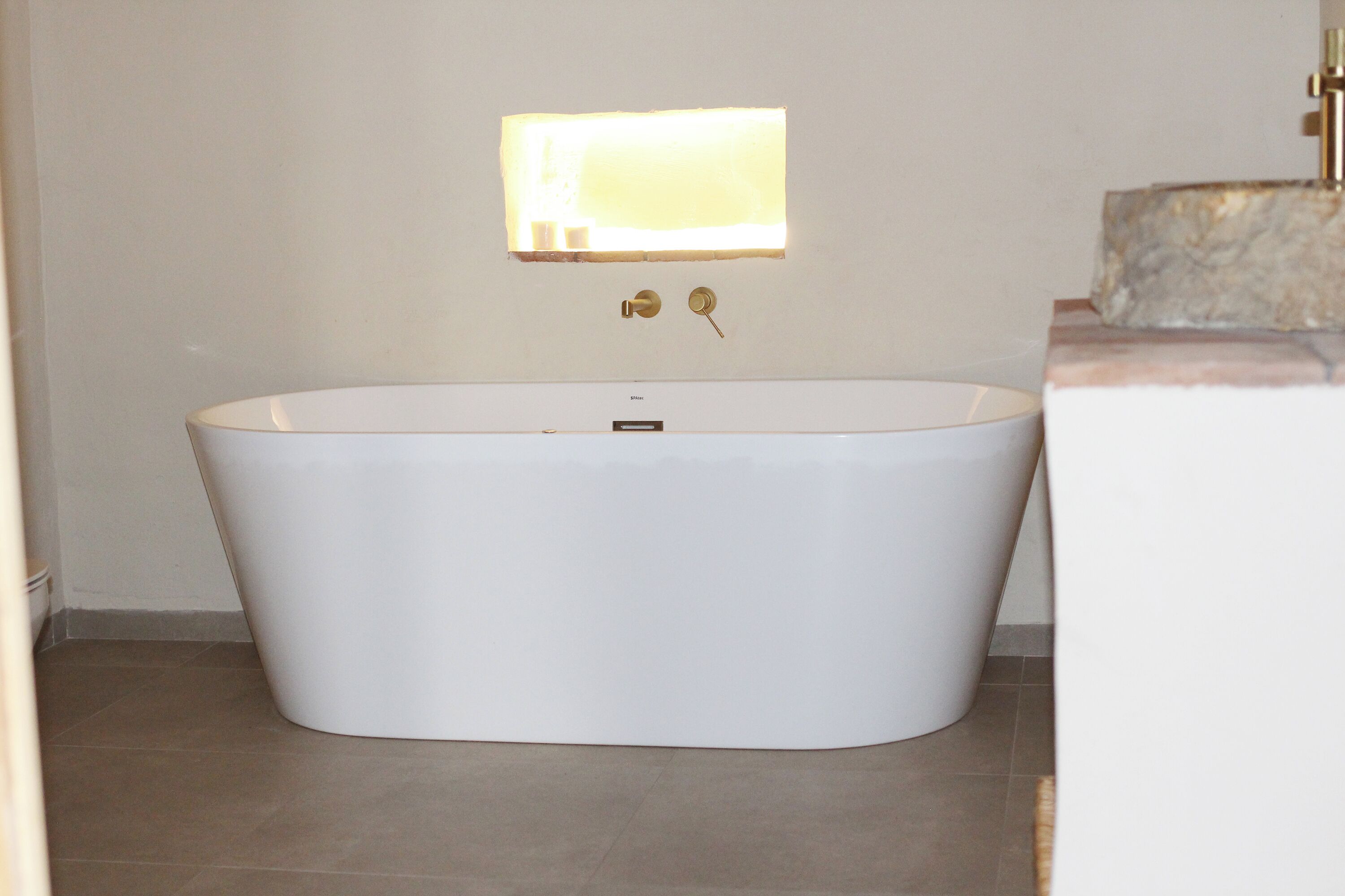 Ein modernes Badezimmer mit freistehender Badewanne, einer Wandleuchte und einem Marmorschmuckstück.