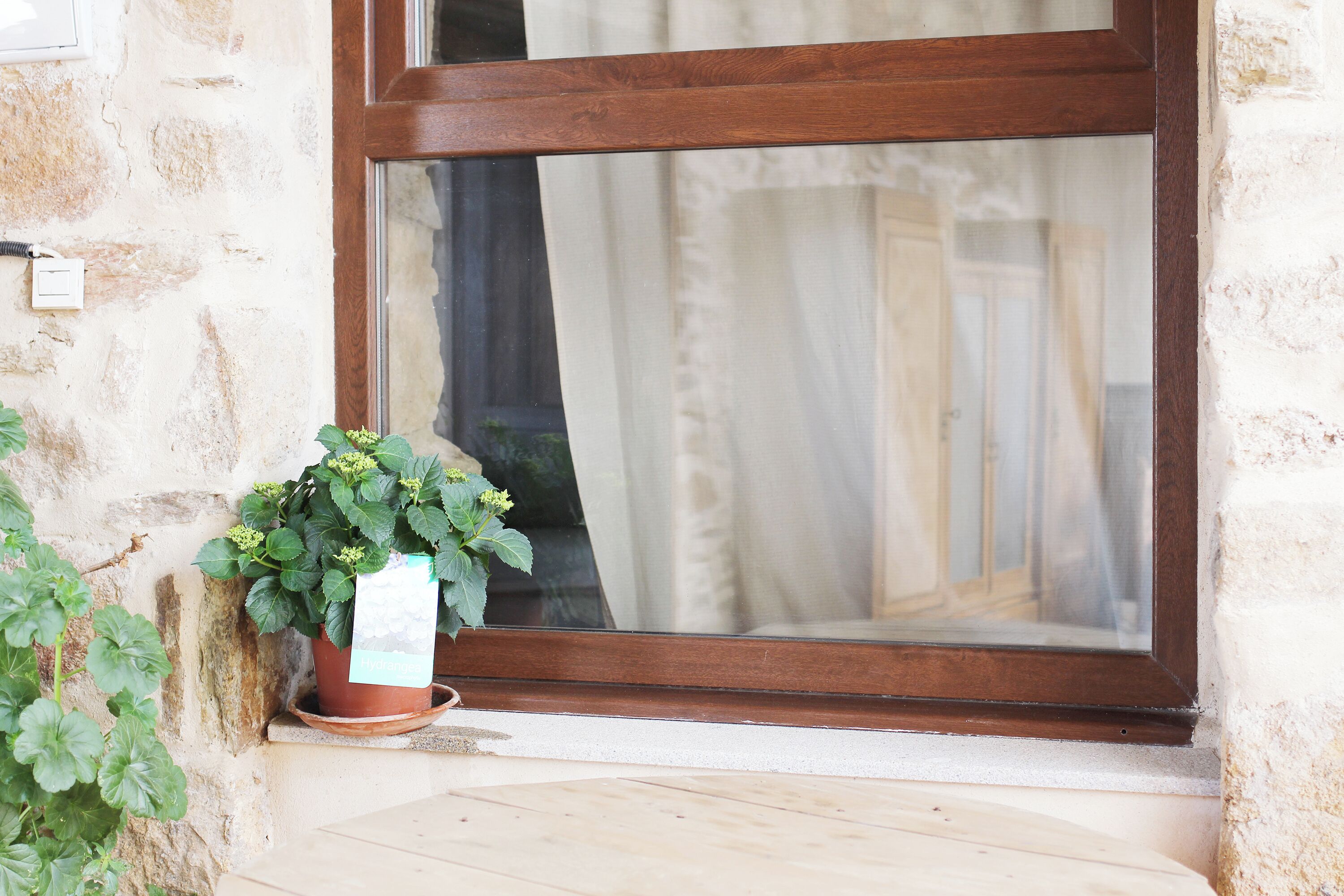 Una ventana con marco de madera y una maceta a su lado.