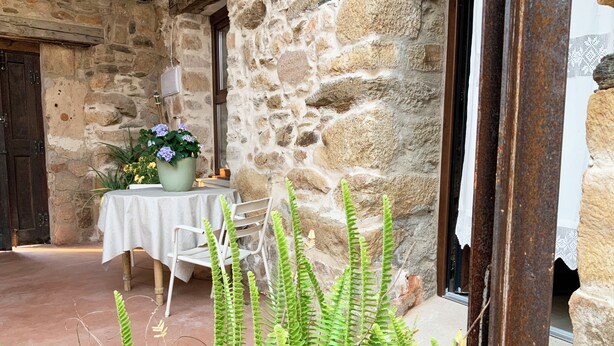 A stone building with a table and chairs set up outside. - La Grulla Dorada (Perales del Puerto)