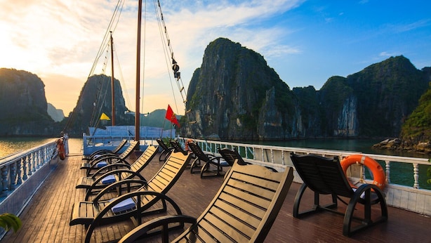 Une terrasse dotée de rangées de chaises longues et d’une bouée de sauvetage, offrant une vue sur une étendue d’eau bordée de falaises rocheuses.