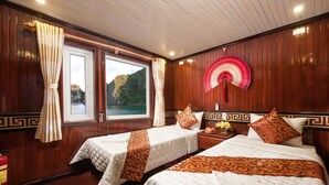 Une chambre avec deux lits, un lambris en bois, une grande fenêtre donnant sur une vue sur la montagne et un ventilateur traditionnel.