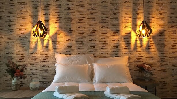 A hotel room with a bed, two wall-mounted lamps, and a textured wall. - Casa Aldeia da Lapa (Sernancelhe)