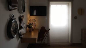 A room with a wooden table, a wall-mounted clock, a decorative vase, and a television. - Casa Aldeia da Lapa (Sernancelhe)