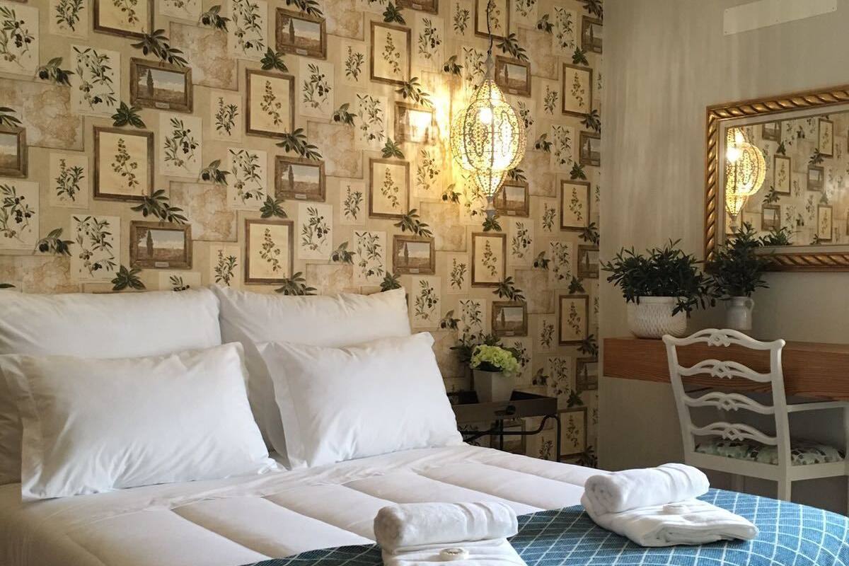 Uma cama bem arrumada com lençóis brancos, um cobertor xadrez azul e duas toalhas dobradas sobre a cama.