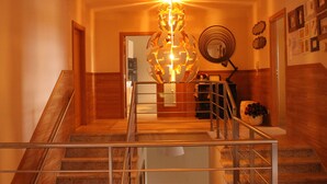 A staircase with a metal railing, a decorative globe light fixture, and a wall with framed pictures. - Casa Aldeia da Lapa (Sernancelhe)