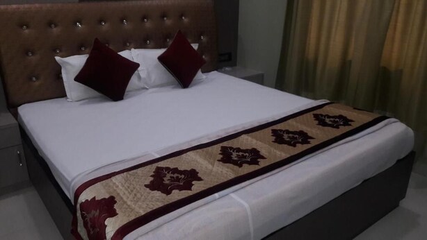 A neatly made bed with a white duvet and a decorative throw blanket. - Hotel Shreemoyee Inn (Guwahati)