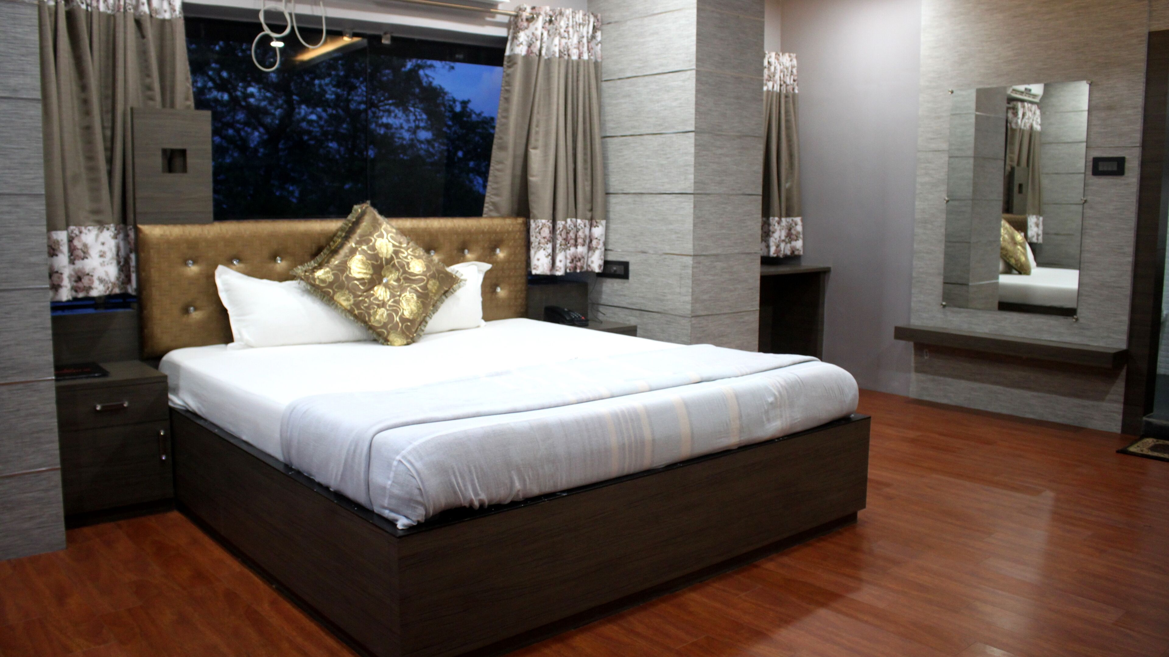 A modern bedroom with a large bed, wooden headboard, and a nightstand.