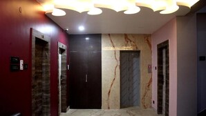 A hallway with elevators, marble walls, and a modern ceiling design.
