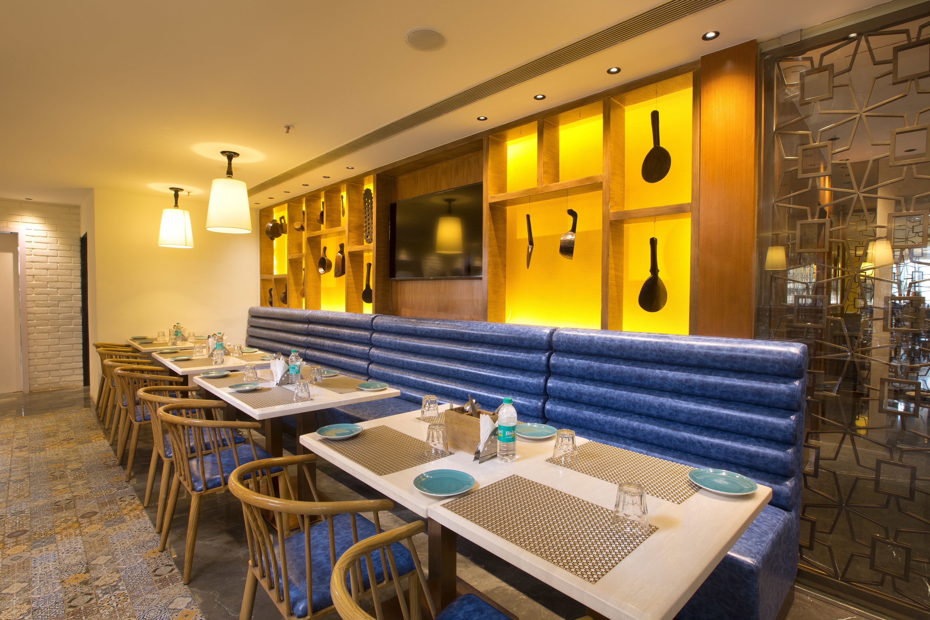A restaurant with long tables, blue cushioned booths, and hanging kitchen utensils.