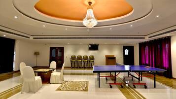 A spacious room with a ping pong table, a foosball table, and several chairs.