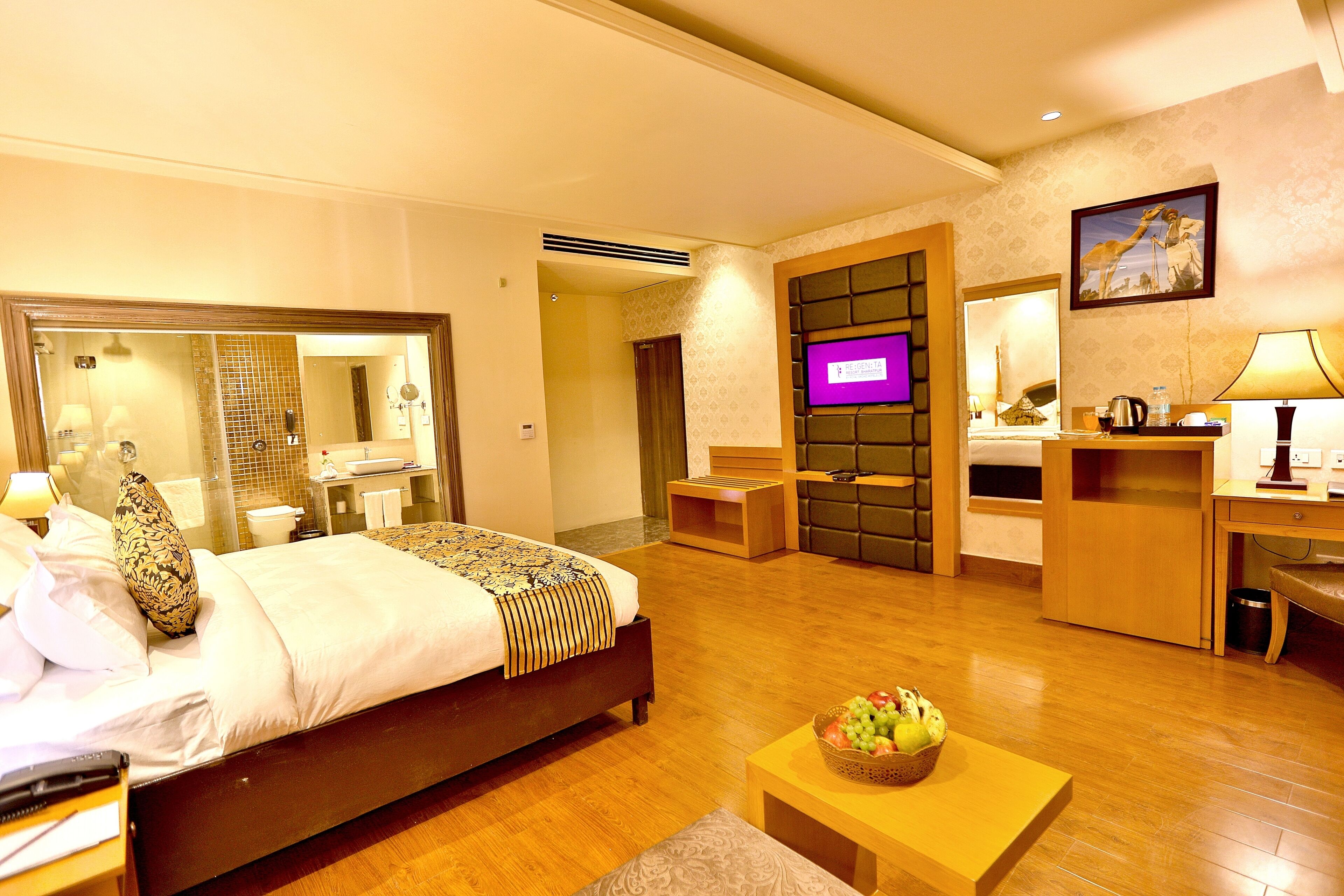 A hotel room with a bed, a desk, a chair, a TV, and a bathroom.