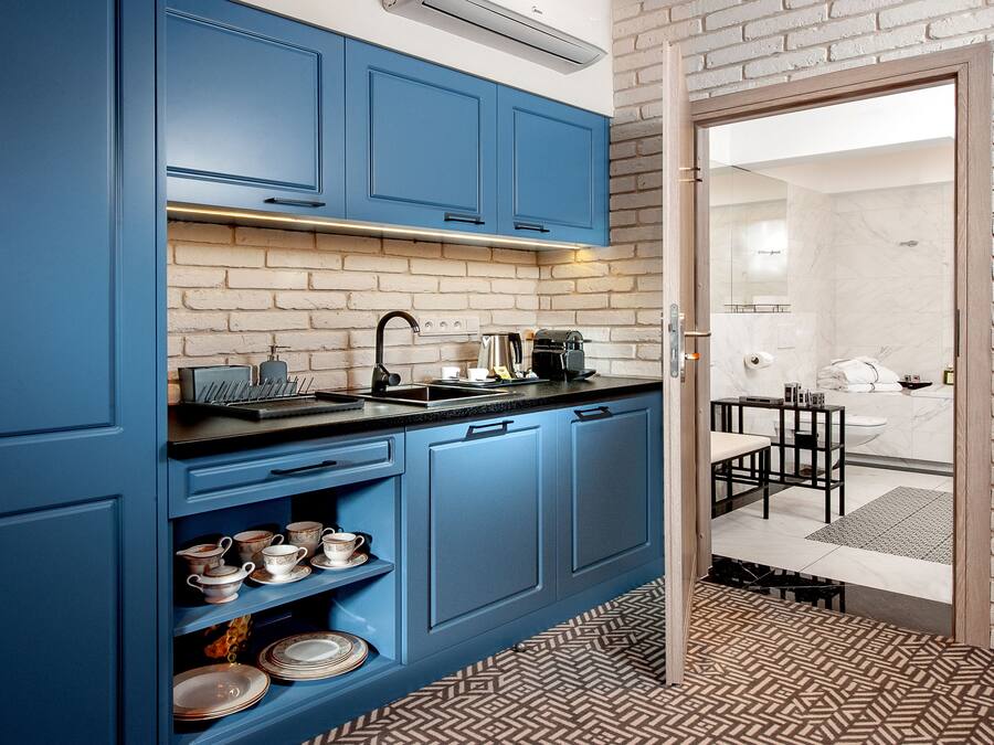 Una cucina moderna con mobili blu, un piano di lavoro nero e una parete in mattoni.