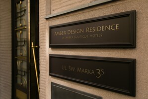 A hotel sign with the name "Amber Design Residence by Amber Boutique Hotels" and the address "UL ŚW. MARKA 35".