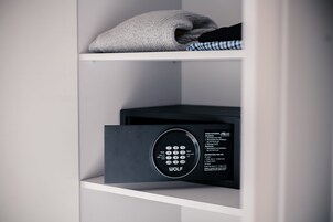 Una habitación moderna y minimalista con una caja fuerte empotrada y una toalla doblada cuidadosamente en el estante.