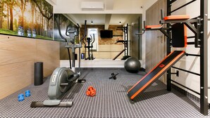 A home gym with exercise equipment, a treadmill, weights, and a wall-mounted TV. - Amber Design Residence (Kraków)