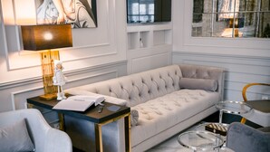 A modern living room with a tufted sofa, a side table, a lamp, and a small decorative figure. - Amber Design Residence (Kraków)