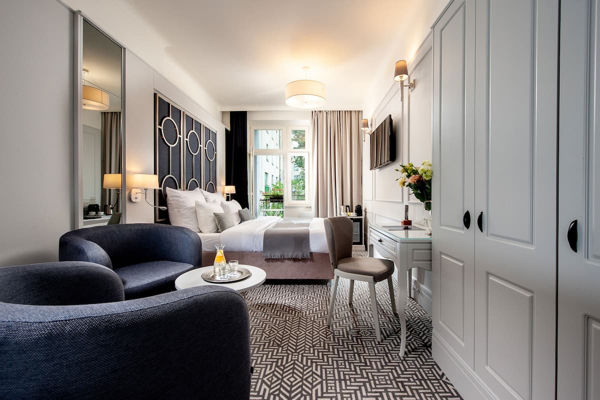 Una habitación de hotel moderna con cama, sofá, escritorio y televisión.