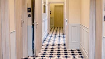 A hallway with a checkered floor pattern, doors on both sides, and a light fixture on the ceiling.