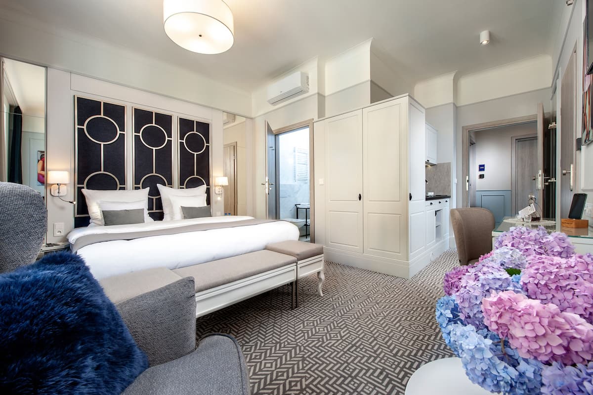 Una habitación de hotel moderna con una cama grande, un escritorio, una silla y un armario.