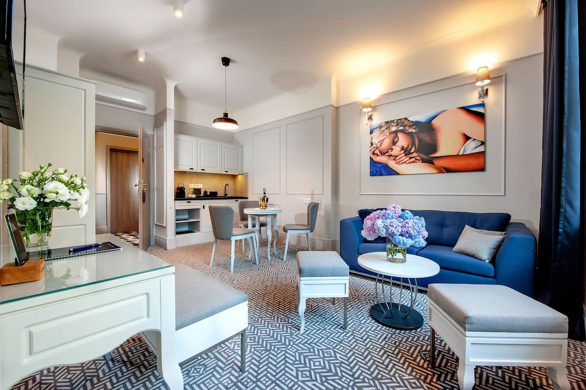 Una sala de estar moderna con un sofá azul, una mesa de centro de vidrio y un comedor con una mesa pequeña y sillas.