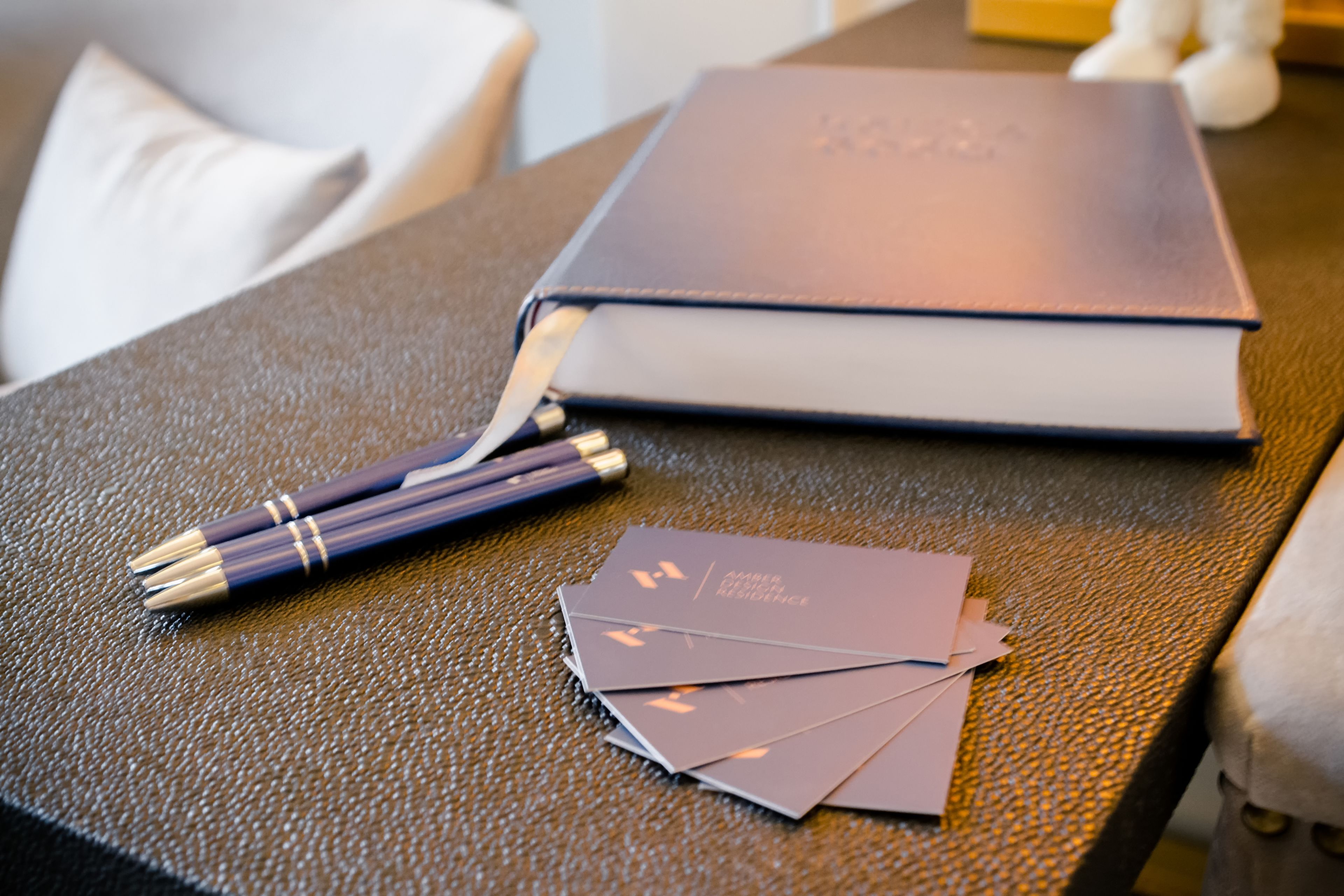 Un carnet à la couverture en cuir, un stylo et quelques feuilles de papier sur une surface texturée.