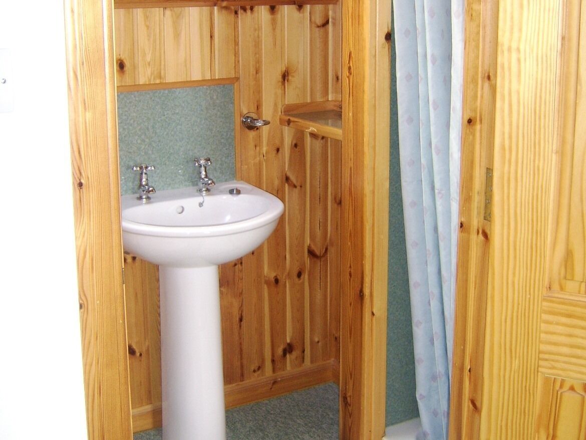 Ein Badezimmer aus Holz mit einem weißen Waschbecken und einem Spiegel.