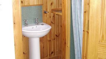 Ein Badezimmer aus Holz mit einem weißen Waschbecken und einem Spiegel.
