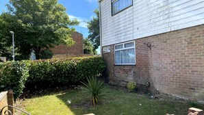 A residential building with a brick facade, a window with a curtain, and a sign indicating 'Chelsea Gardens'. - Huku Kwetu - Chelsea Garden (Dunstable)