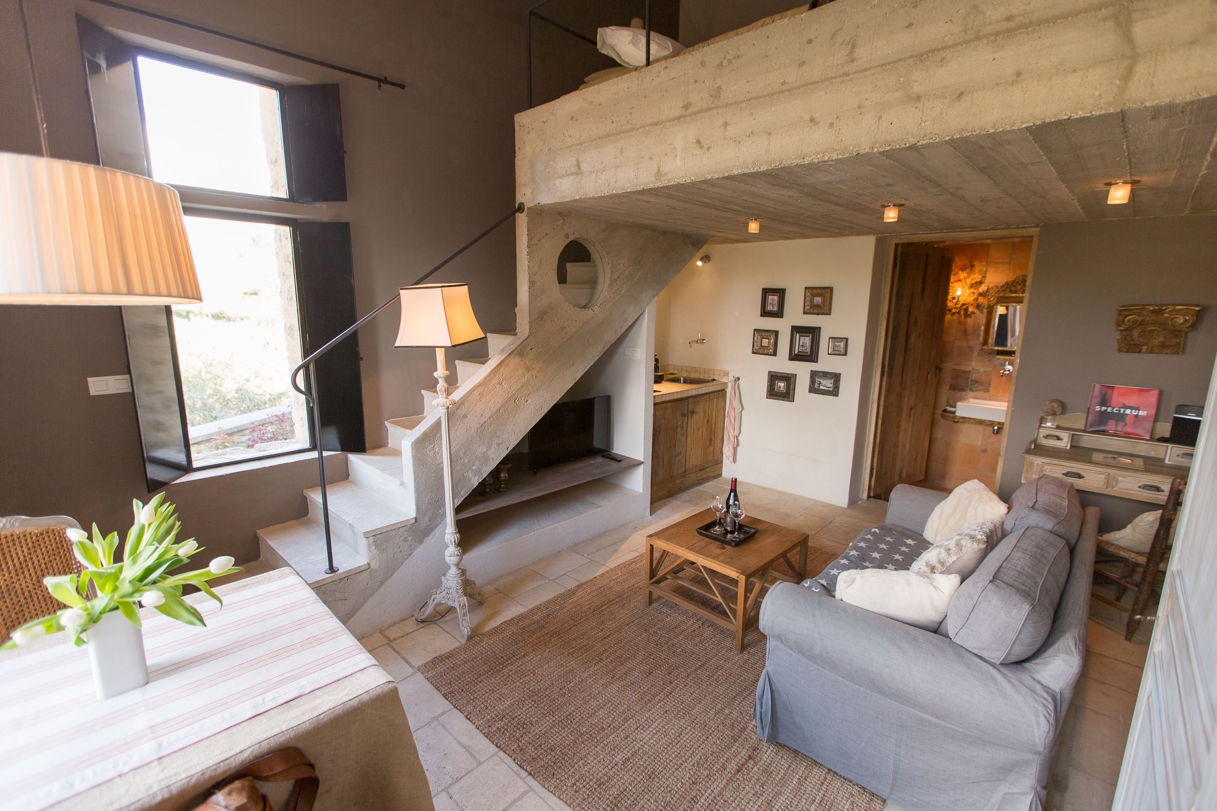 A modern living room with a staircase, a sofa, a coffee table, and a dining area.