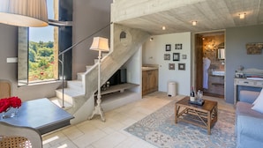 A spacious living area with a staircase leading to a loft, a dining area with a view, and a bathroom with a bathtub and shower. - Domaine Les Roullets (Oppede)