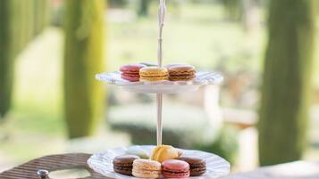 A tiered dessert stand with macarons and a cup of coffee on a tray.