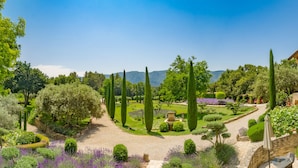 A well-maintained garden with a variety of trees, a stone pathway, and a pergola structure. - Domaine Les Roullets (Oppede)
