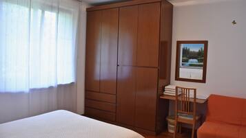 Une chambre à coucher comprenant un lit, une armoire, un bureau avec une chaise et un tableau encadré accroché au mur.