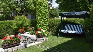A garden with a stone bench, potted plants, and a pergola.