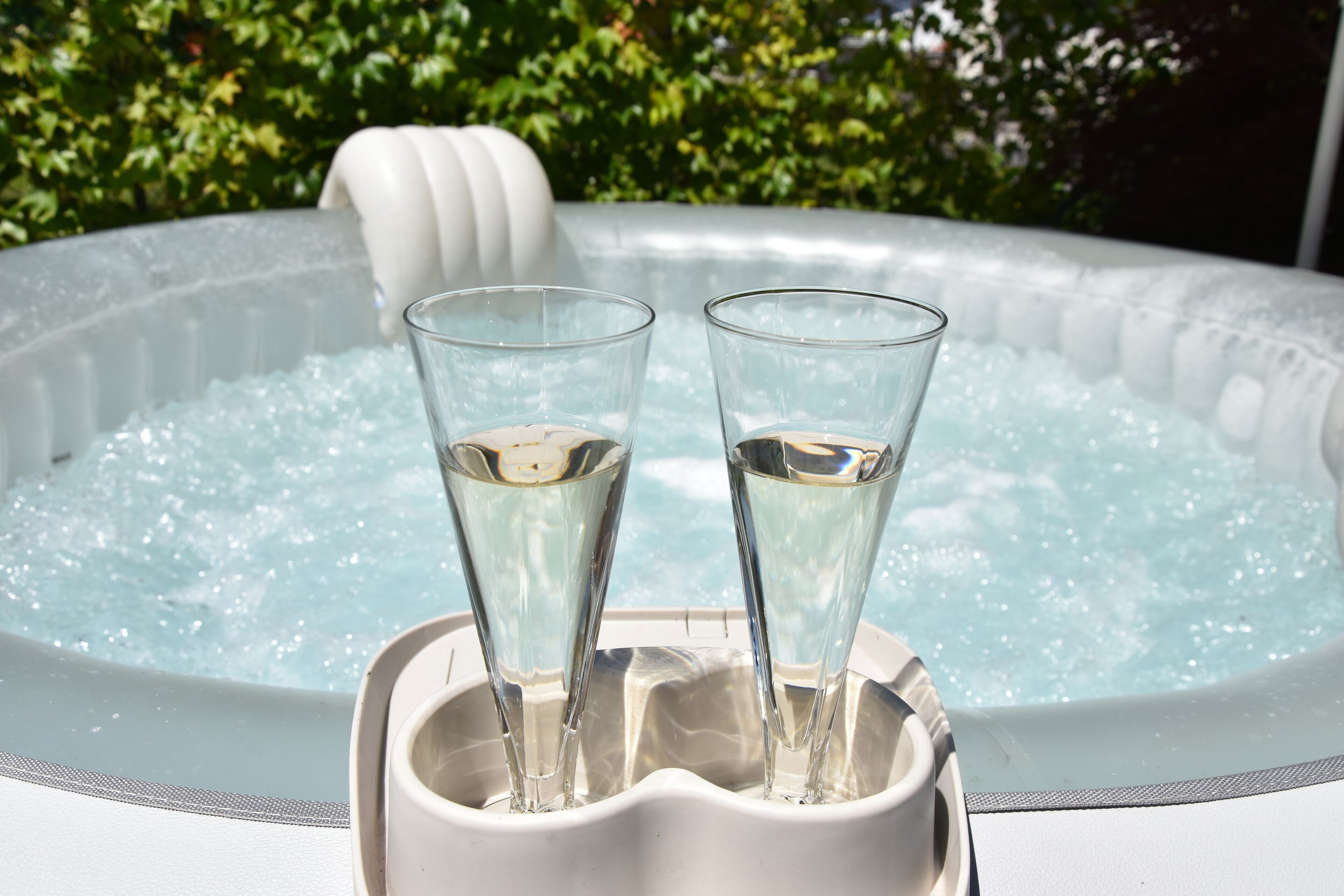 Two glasses of water in a white hot tub with a white exterior and a textured surface.