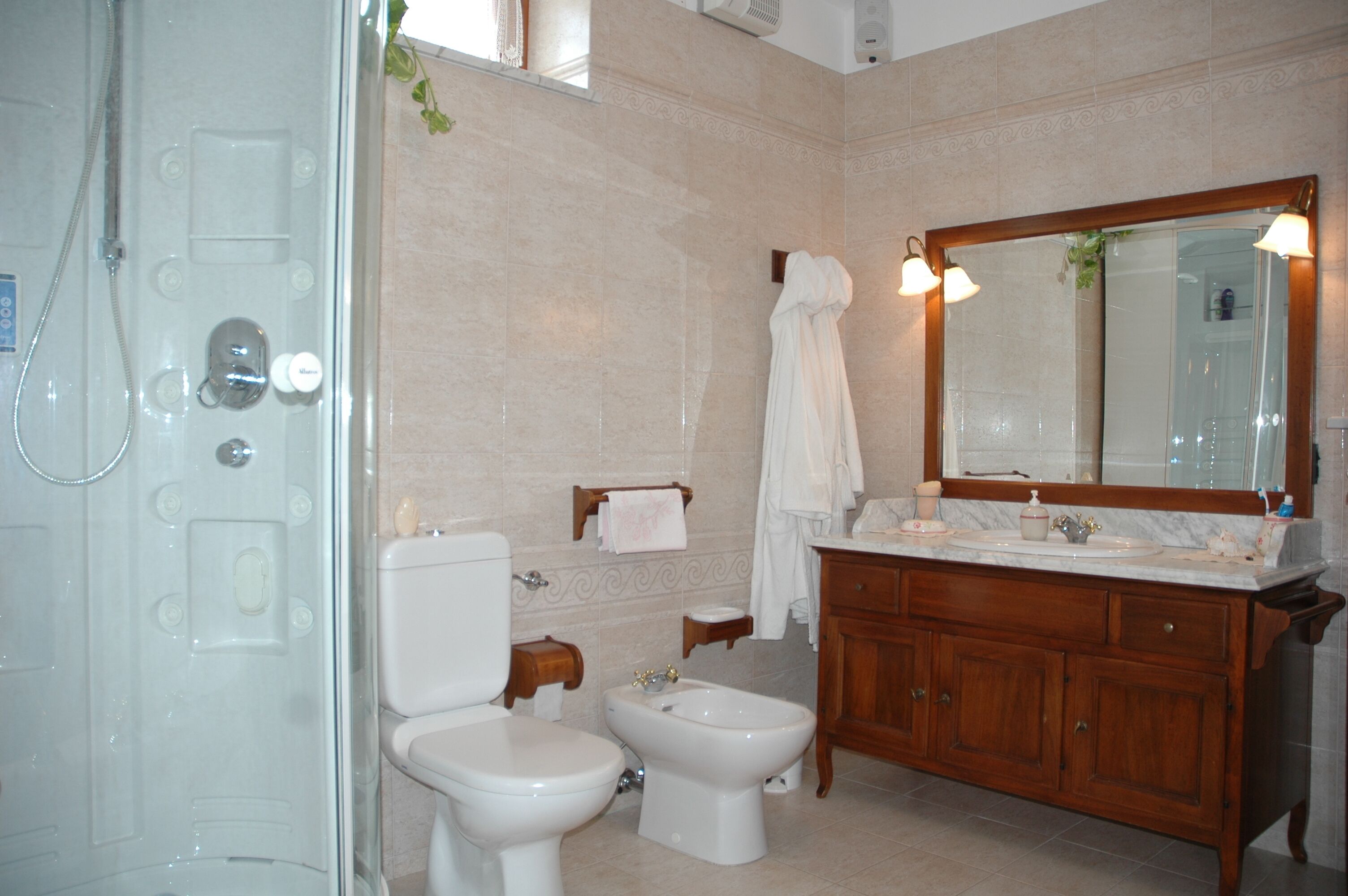 Un baño con inodoro, bidé, tocador con espejo y zona de ducha.