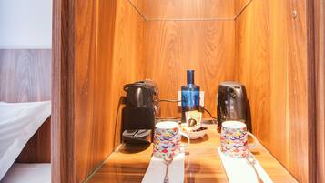 Una habitación compacta de madera con una mesa de vidrio mostrando una cafetera, dos tazas y una cuchara.