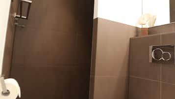 A modern bathroom with a toilet, a shower area, and a mirror.