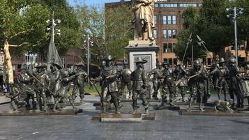 Ein historisches Denkmal mit einer zentralen Statue, umgeben von einer Gruppe Soldaten.