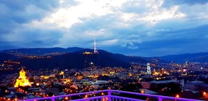 A cityscape at dusk with a prominent tower and a lit-up church. - Upstairs Hotel Tbilisi (Tbilisi)